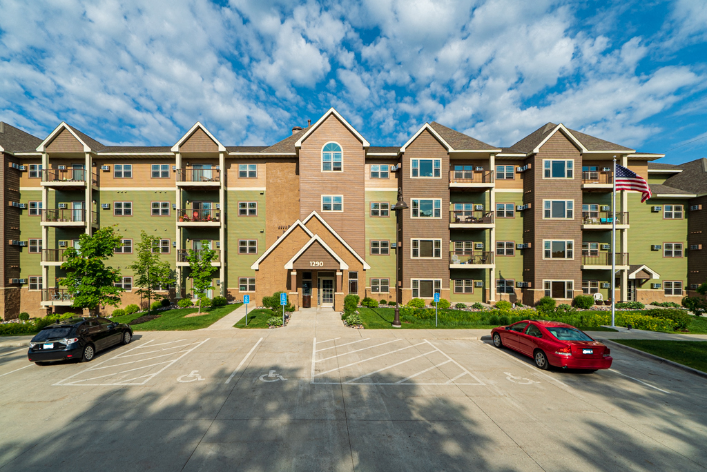 an apartment building with a parking lot and a red car