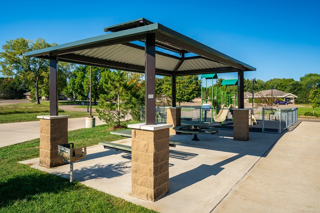 a pavilion with benches and a playground in a park