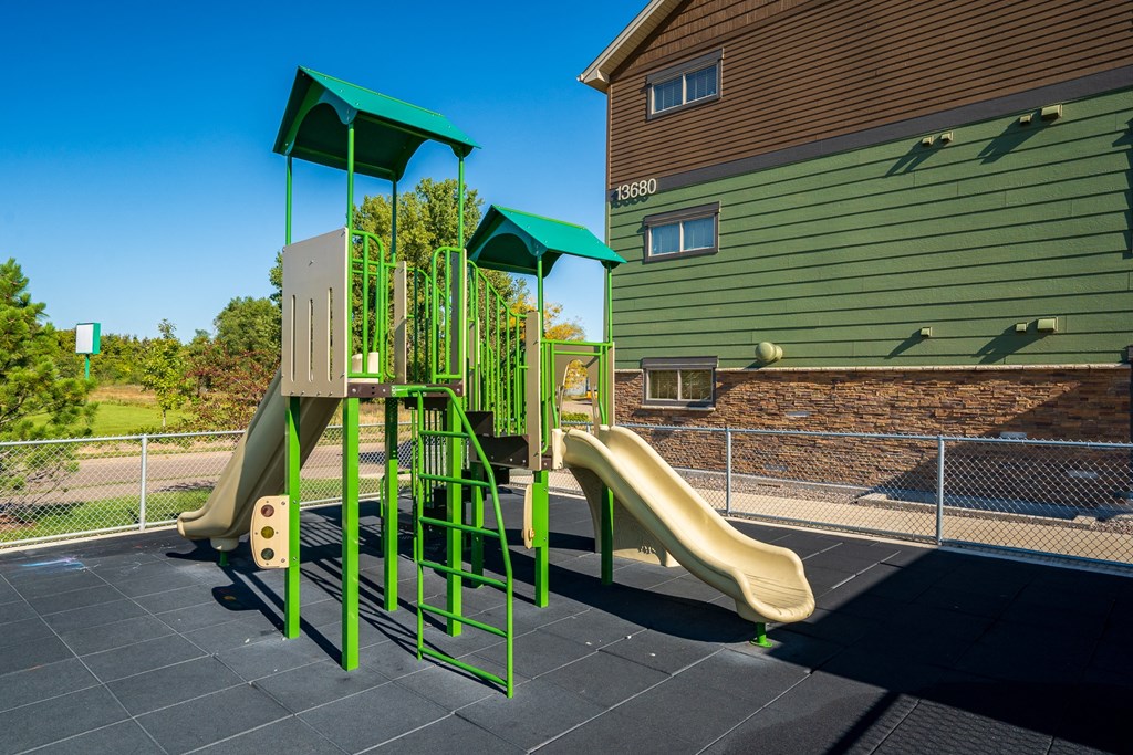a childrens play area with slides and swings in front of a house