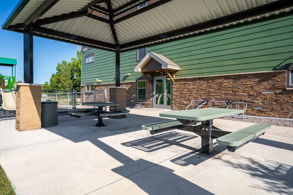a covered patio with picnic tables and a brick building
