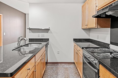 A kitchen with a black counter top and a stove.