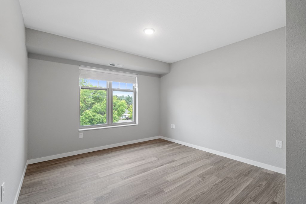 A room with a window and wooden flooring.