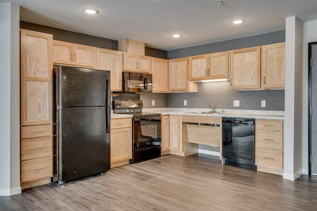 A kitchen with wooden cabinets and a black refrigerator.