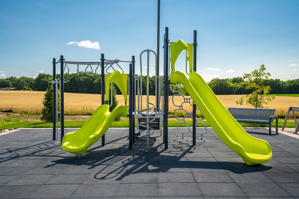 A playground with a green slide and a metal structure.