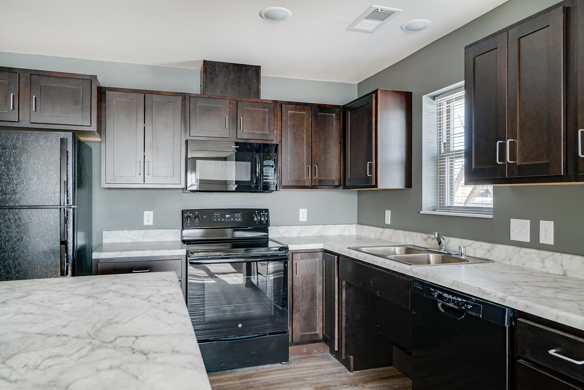 an updated kitchen with dark wood cabinets and marble counter tops