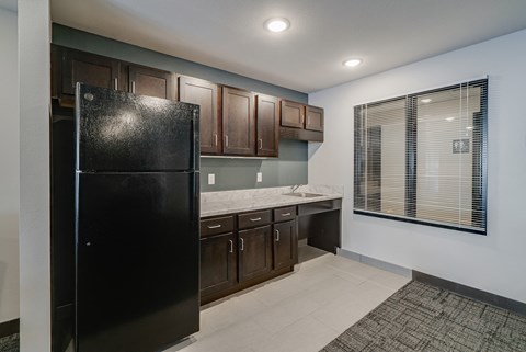 A black refrigerator in a kitchen with brown cabinets.