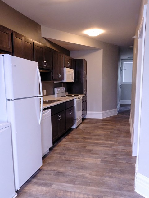 A kitchen with a white refrigerator and wooden cabinets.
