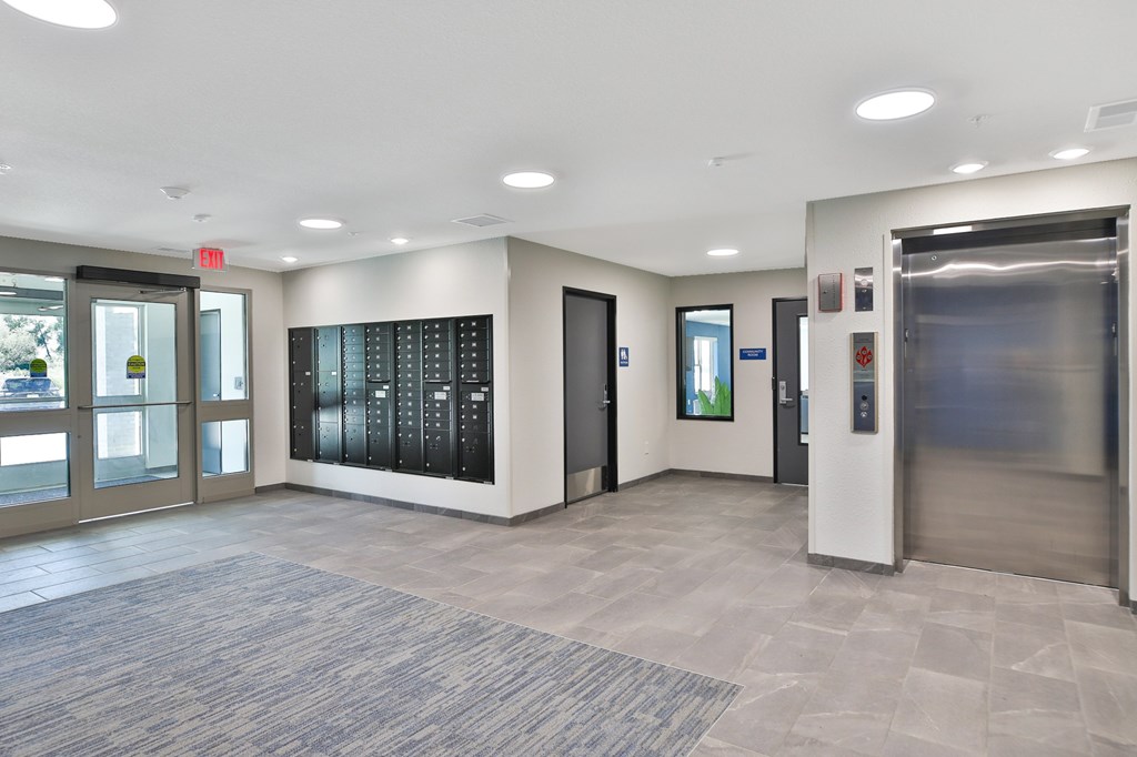 A hallway with a blue carpet and a stainless steel elevator.