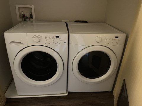 Two white front load washing machines in a small laundry room.