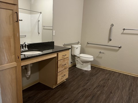 A bathroom with a toilet, sink, and towel racks.