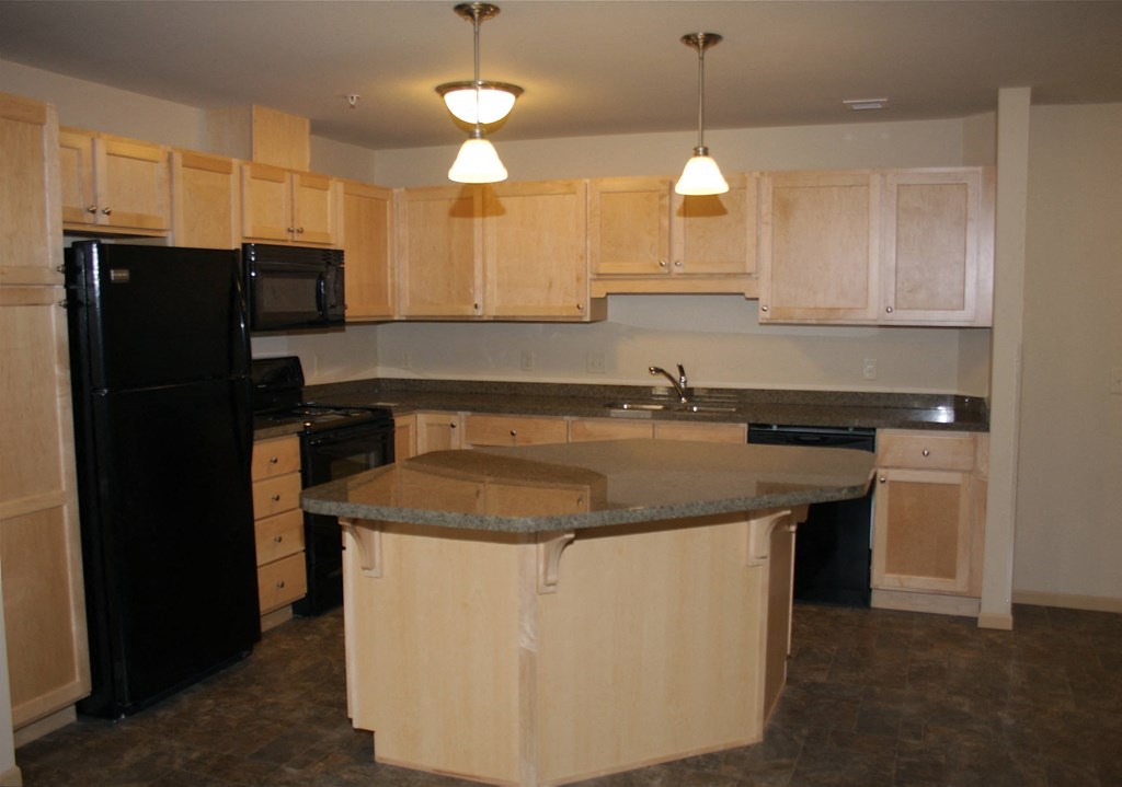 a kitchen with a center island and a black refrigerator
