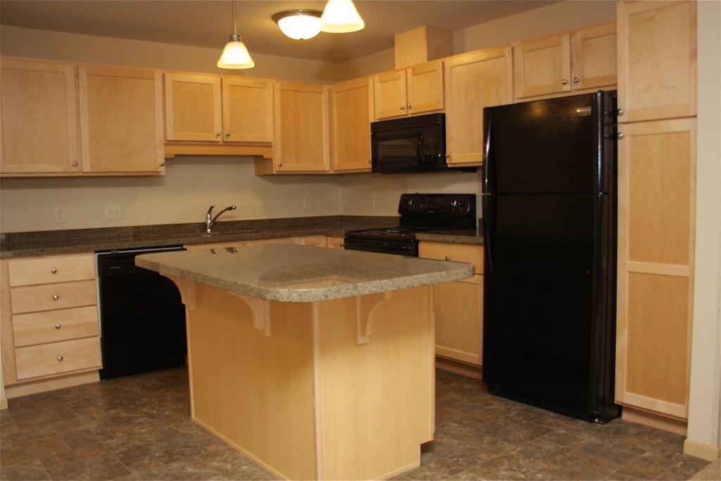 a kitchen with a island and a black refrigerator