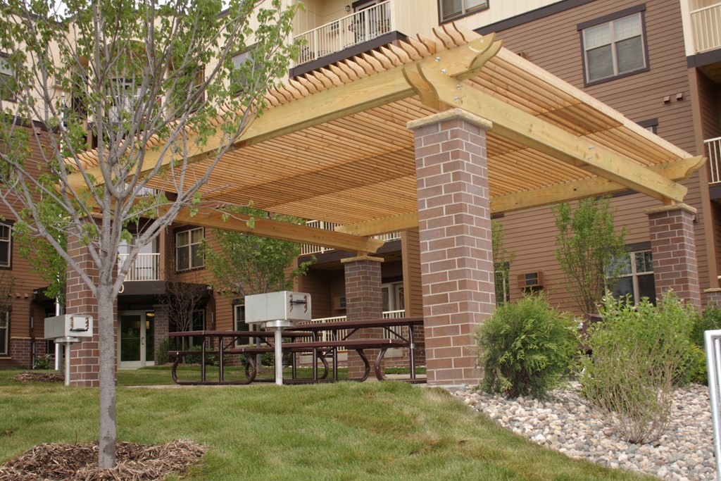 a covered patio with a table and a grill