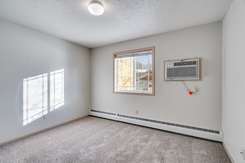 an empty living room with an air conditioner and a window