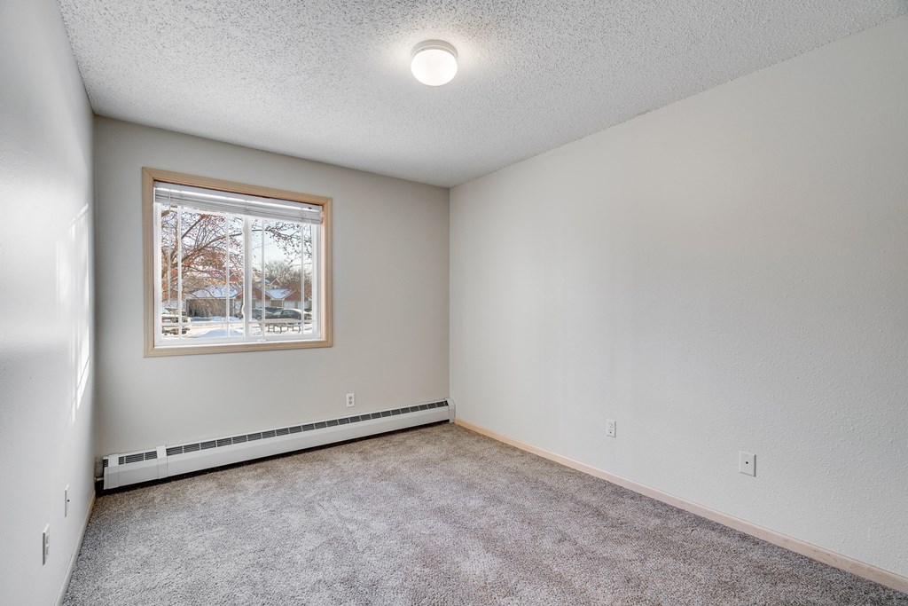 an empty living room with a window and carpet