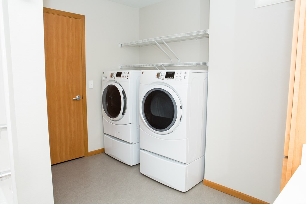 Two white front loading washing machines in a laundry room.