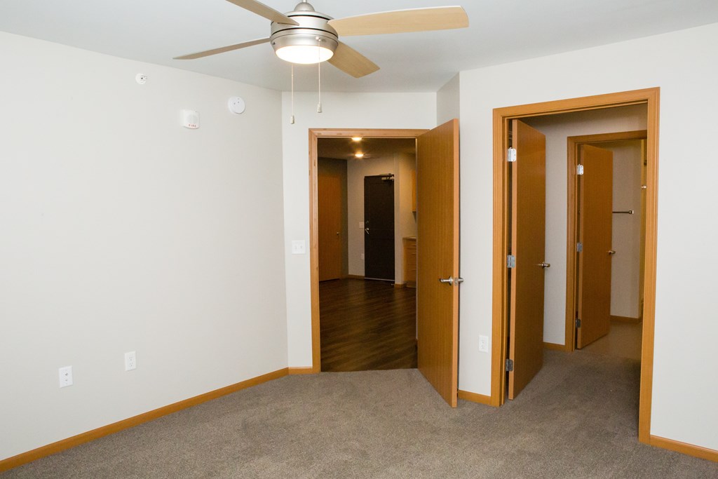 A room with a ceiling fan and carpeted floor.