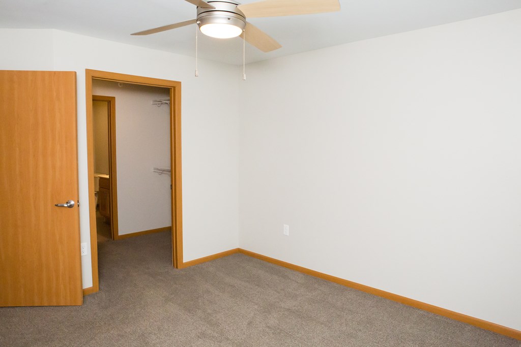 A room with a ceiling fan and a door.