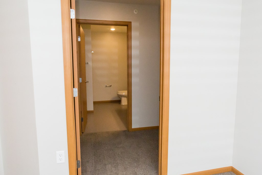 A bathroom with a toilet and sink is visible through an open door.