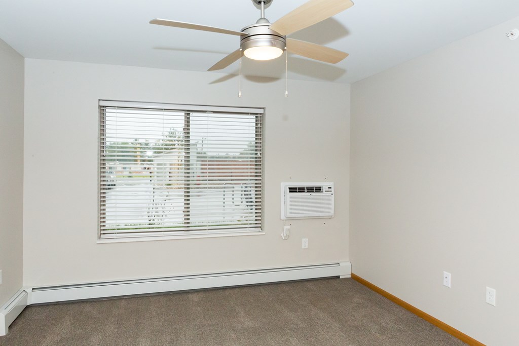 A room with a ceiling fan and a window with blinds.