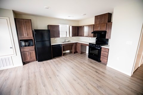 A kitchen with black appliances and wooden floors.