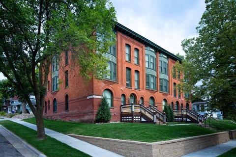 A red brick building with green trees in front.