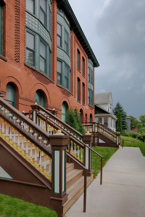 A red building with a staircase leading to the front door.