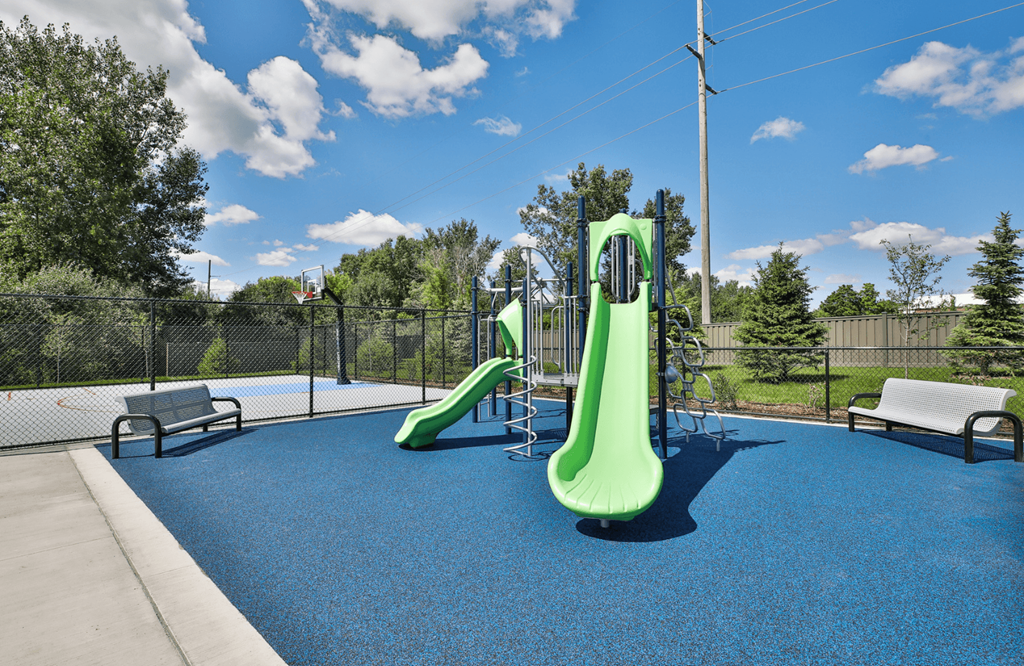A playground with a blue surface and a green slide.