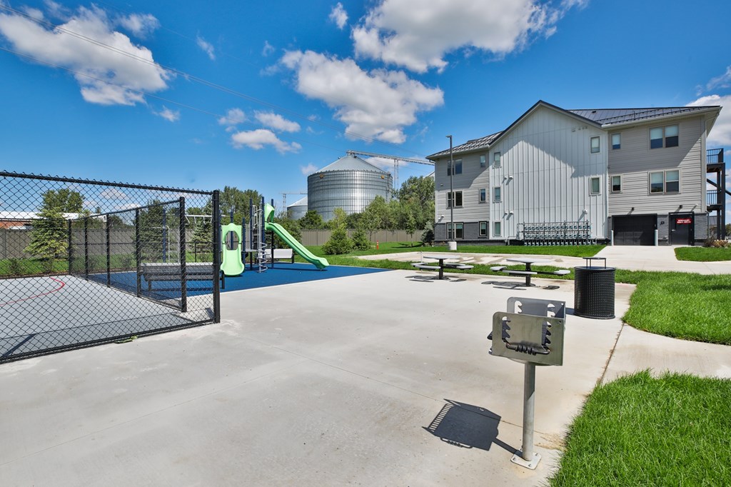 A playground with a slide and a fence in front of a building.