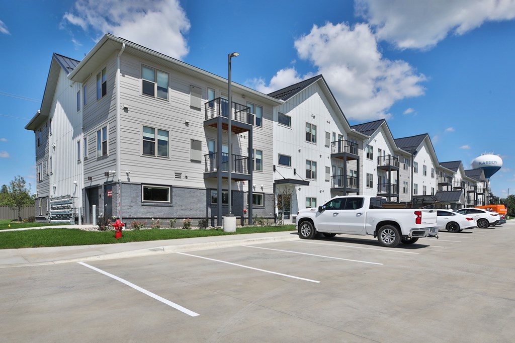 A white truck is parked in a parking lot in front of a building.