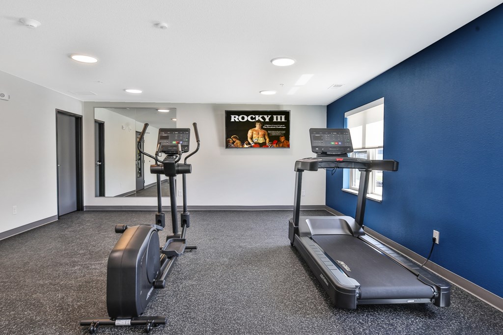A gym with a row of treadmills and elliptical machines.