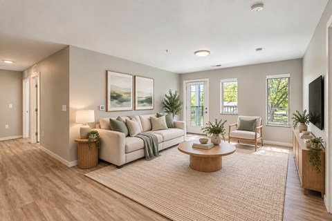 A living room with a white couch, a coffee table, and a television.