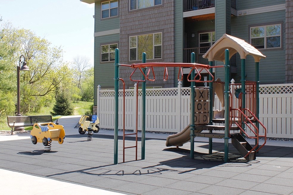 a playground with a swing set in front of a house