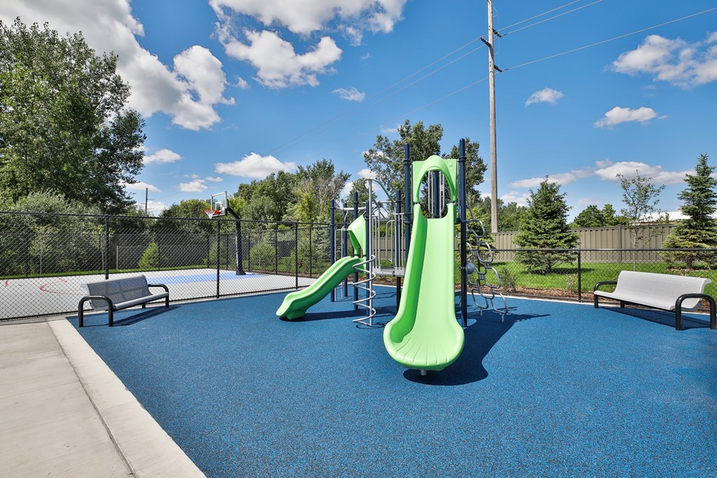 A playground with a blue surface and a green slide.
