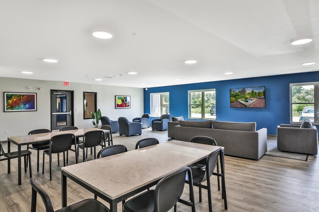 A room with tables and chairs and a blue wall.