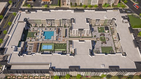 A large, open courtyard surrounded by buildings with a pool and a tennis court.