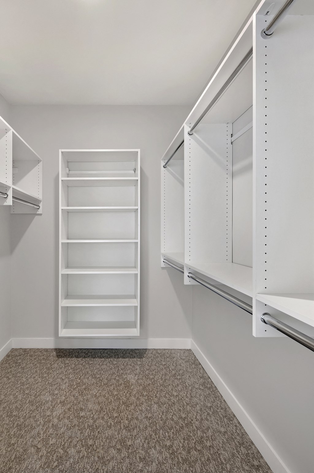 an empty closet in a home with white shelves