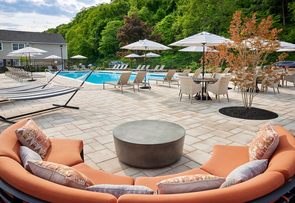 a patio with chairs and umbrellas near a swimming pool at Heritage Oyster Bay, NY