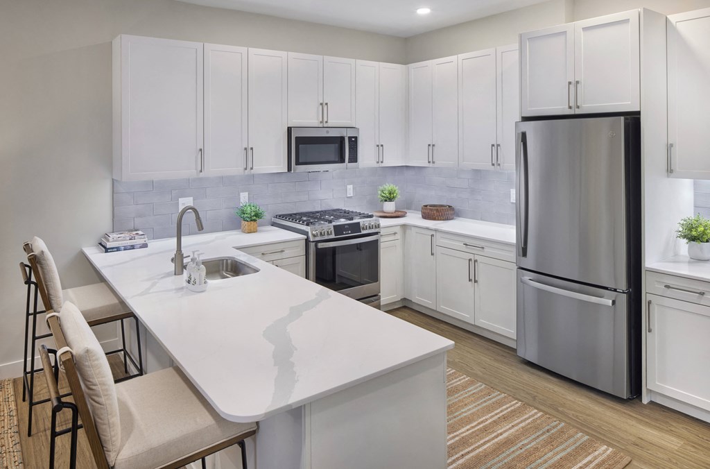 a white kitchen with stainless steel appliances and a white counter top