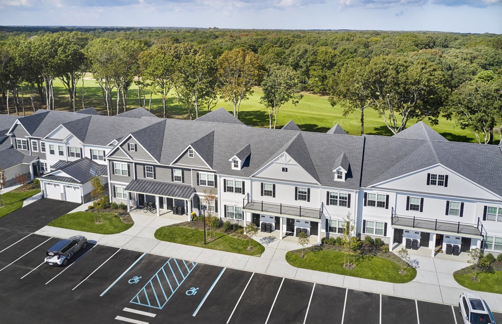 an aerial view of an apartment complex with parking lot and trees