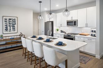 a kitchen with white cabinets and a large white island with a white quartz countertop