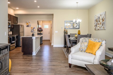 A well-lit, spacious kitchen and living room with a white sofa and wooden floors.