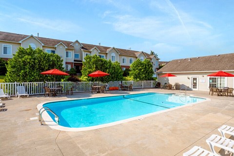 a swimming pool with chairs and umbrellas in front of a building