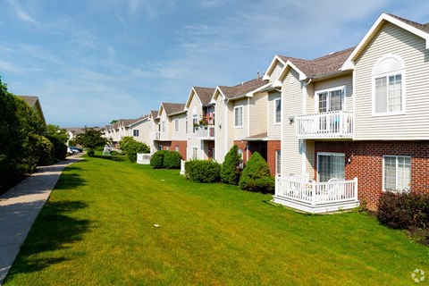 a row of houses with a green lawn and a sidewalk