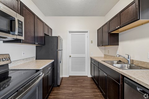 A kitchen with dark brown cabinets and a black refrigerator.