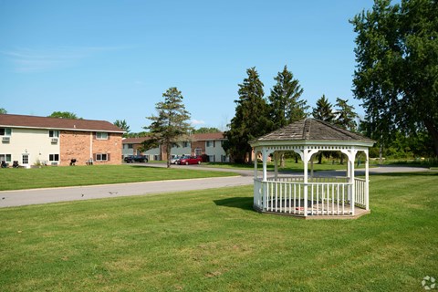 A gazebo sits in the middle of a grassy field.