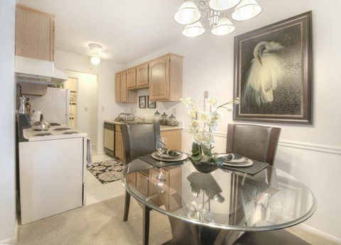 Dining space with modern glass table and kitchen view at Chili Heights Apartments, Rochester, NY