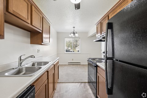 A kitchen with a black refrigerator and wooden cabinets.