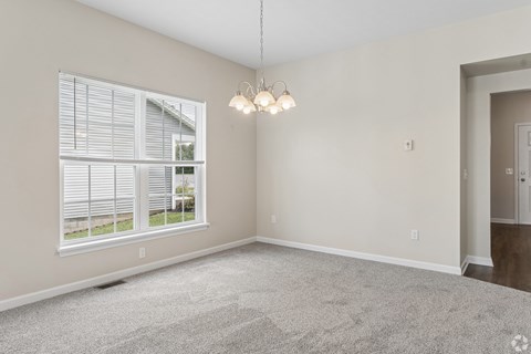 A room with a large window and a carpeted floor.