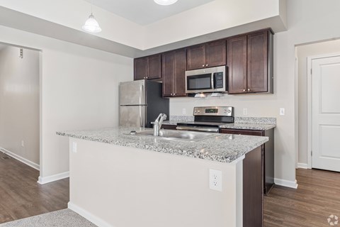 A kitchen with a granite countertop and stainless steel appliances.